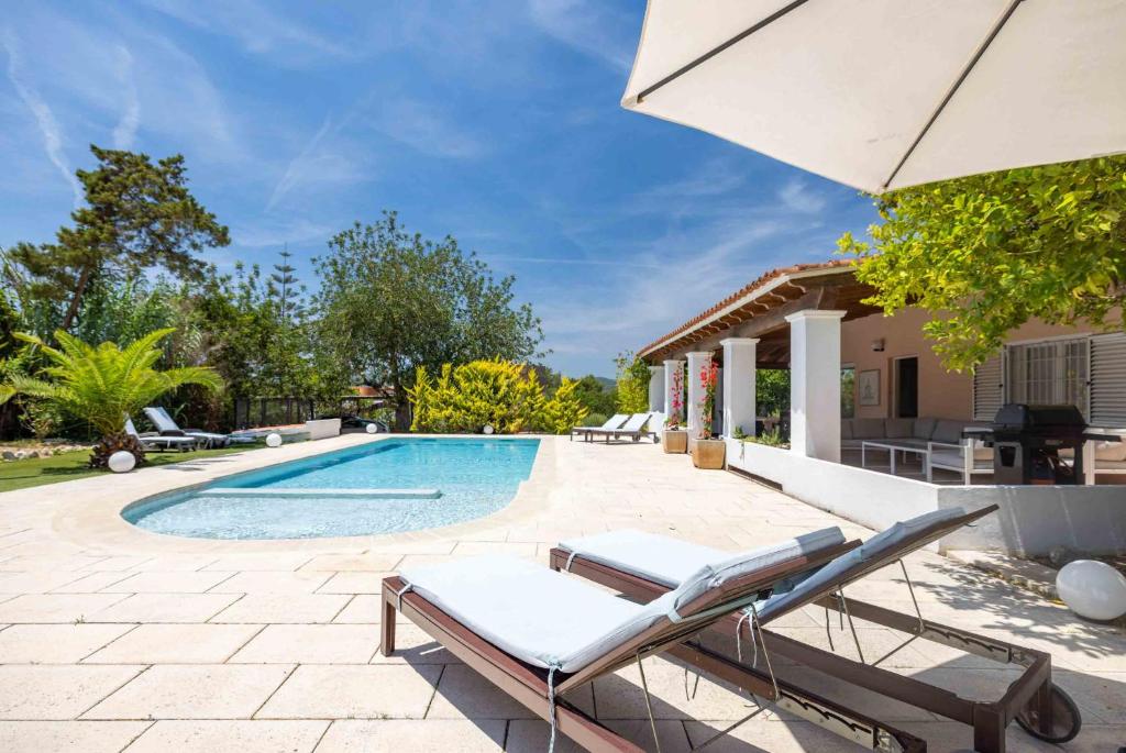 une piscine avec deux chaises longues et un parasol dans l'établissement Villa Albaladejo, à Can Furnet