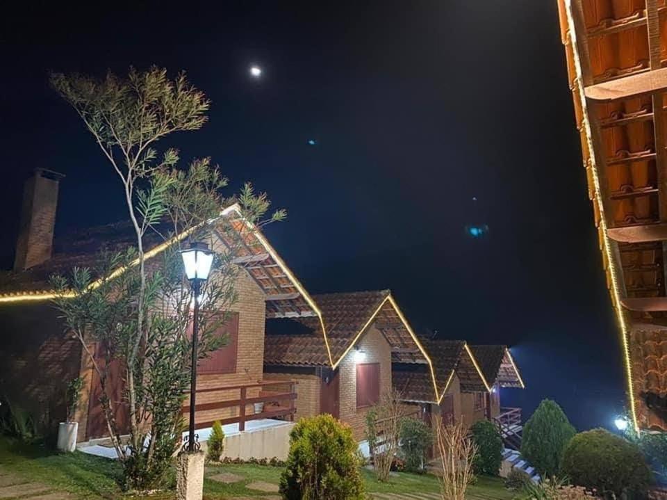 a house at night with the moon in the sky at Pousada Encantus in Monte Verde