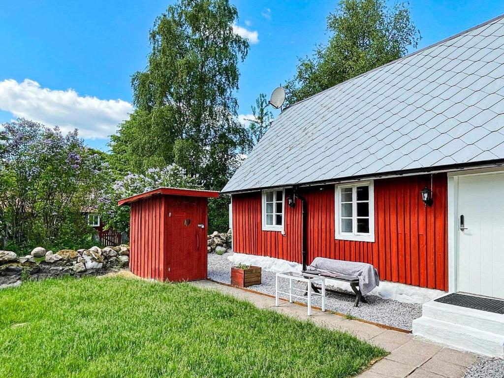 a red shed with a bench in a yard at Holiday home Huaröd in Huaröd
