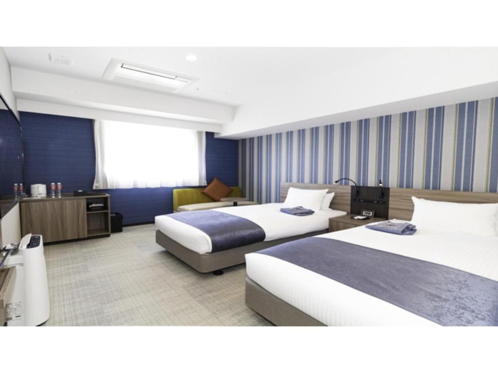 La'gent Stay Hakodate Ekimae - Vacation STAY 75062v في هاكوداته: غرفة فندقية بسريرين واريكة