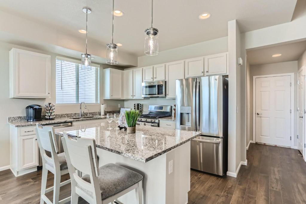 a kitchen with white cabinets and a large island with bar stools at Brand New Townhome with King Suite Near DIA in Denver