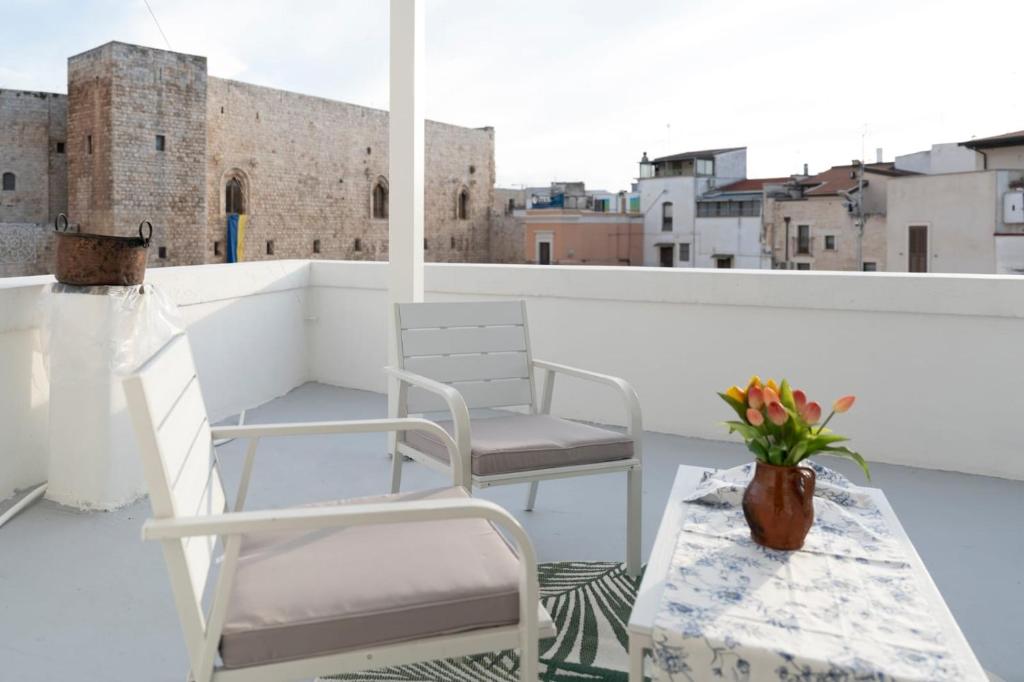 un balcón con 2 sillas y una mesa con un jarrón de flores en suite la corte en Sannicandro di Bari