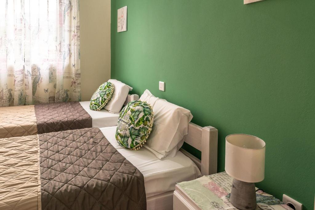 a room with two beds and a green wall at Ritsinia Apartments in Aigio
