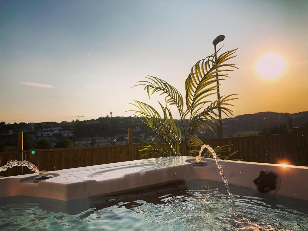 a hot tub with two faucets and the sunset at La pomme d’amour in Saint-Genest-Lerpt
