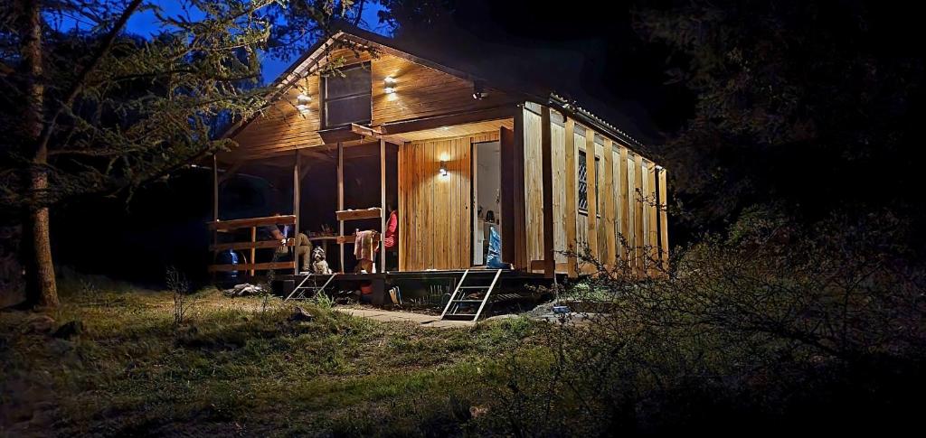 eine kleine Holzhütte mit einer Veranda in der Nacht in der Unterkunft Pod modrzewiem in Ostrzyce