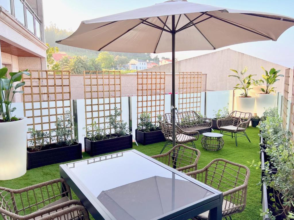 patio ze stołem i parasolem w obiekcie The Cliffs - Piccola Home w mieście Santa Marta de Ortigueira