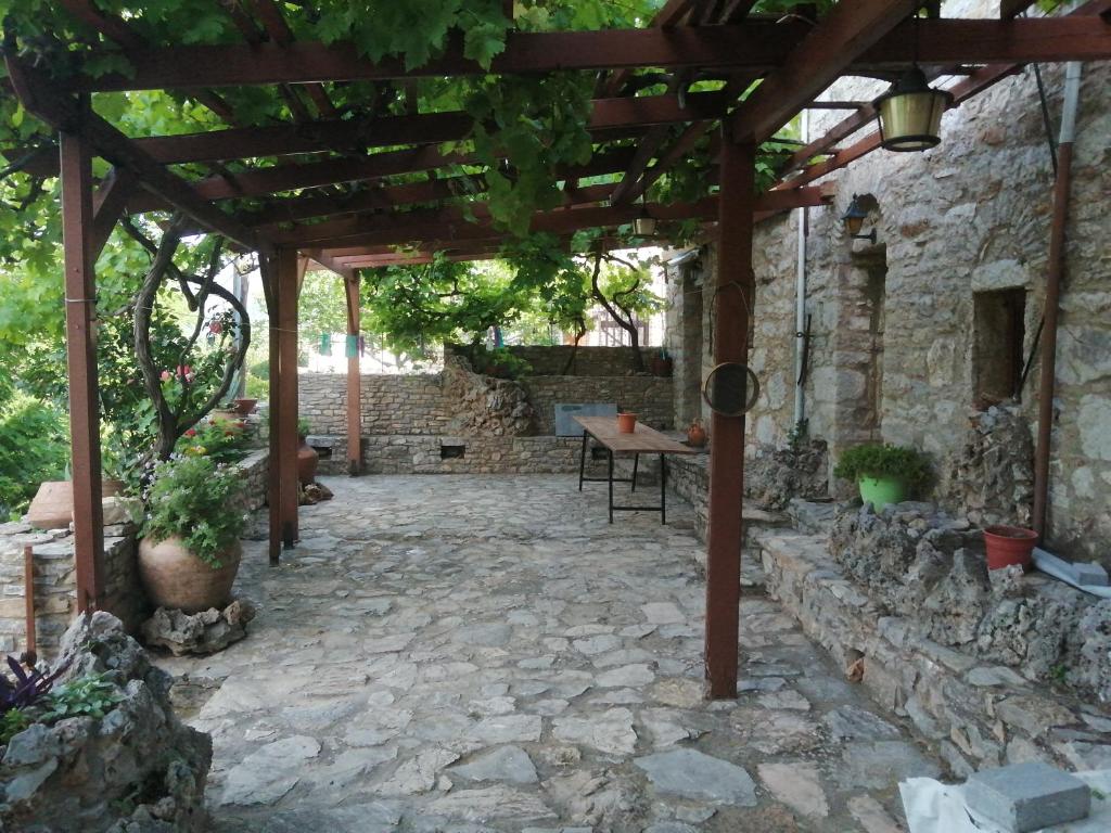 a stone patio with a wooden pergola at ΑΝΑΒΑΤΟΣ ΕΞΟΧΙΚΗ ΚΑΤΟΙΚΙΑ in Chios