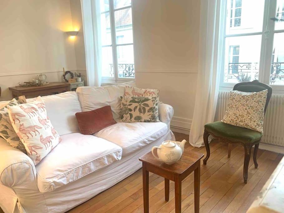 a living room with a white couch and a chair at Appartement de charme proche château et forêt in Fontainebleau