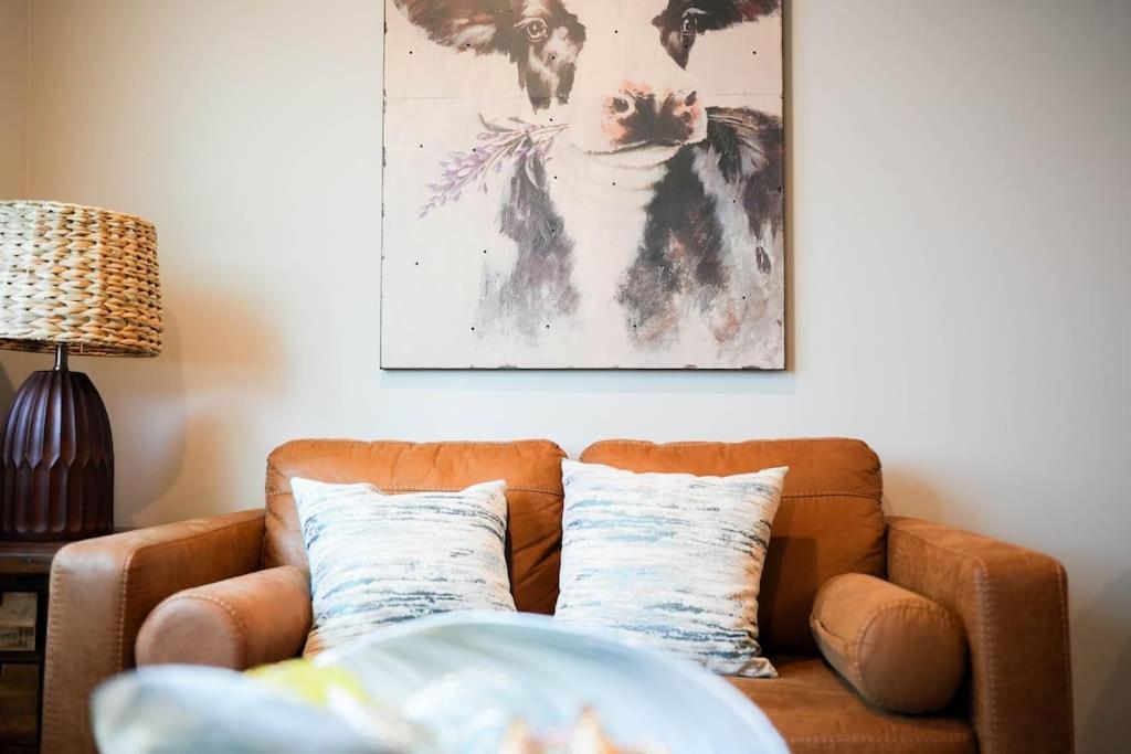 a brown couch in a living room with a painting on the wall at 1 Bedroom Stylish Oasis in Omaha