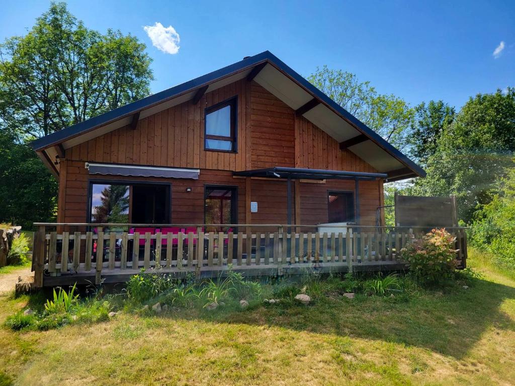 une cabane en rondins avec une véranda et une clôture dans l'établissement Chalet de 3 chambres avec jacuzzi jardin amenage et wifi a Xonrupt Longemer a 5 km des pistes, à Xonrupt-Longemer