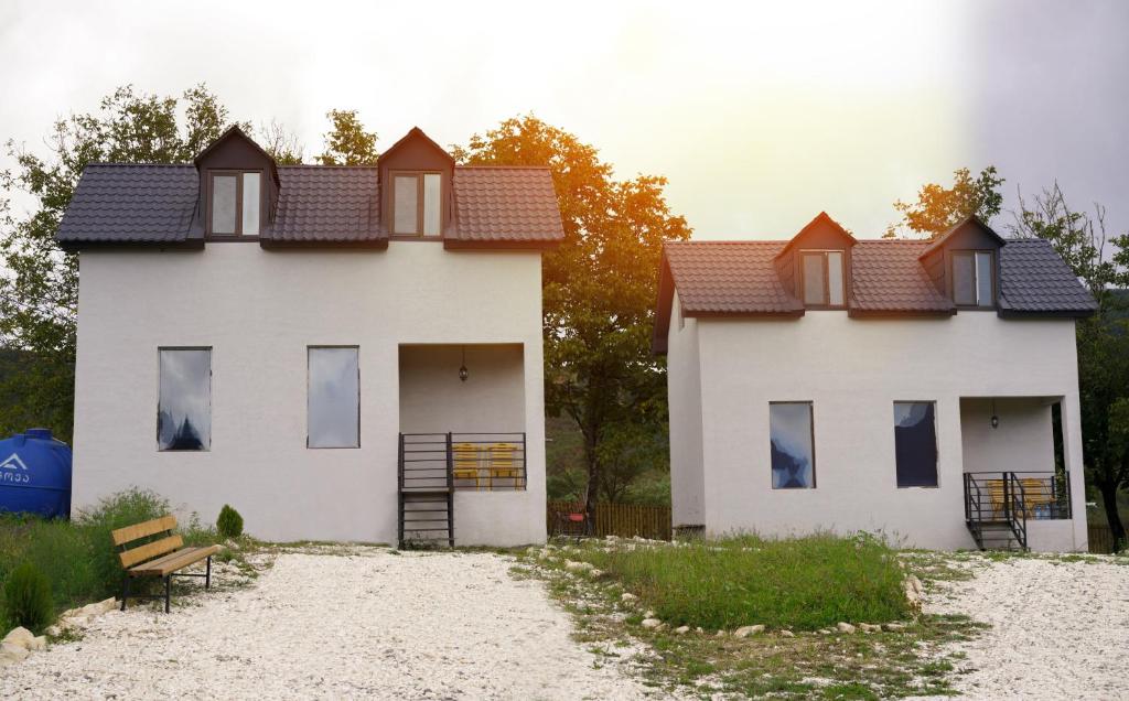 una casa blanca con un banco delante en Racha Twins en Nikortsminda