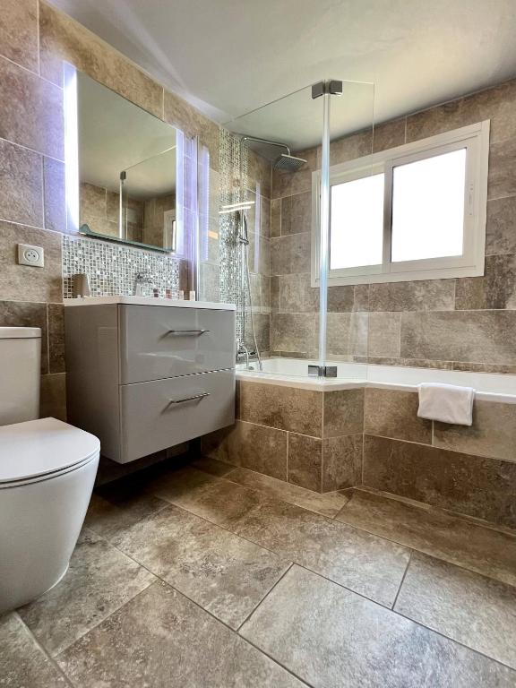 a bathroom with a toilet and a tub and a sink at Hotel La Calanque in Mandelieu-La Napoule