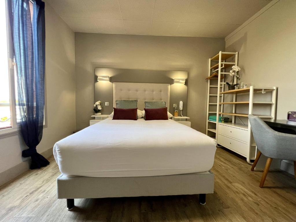a bedroom with a large white bed and a desk at Hotel La Calanque in Mandelieu-La Napoule