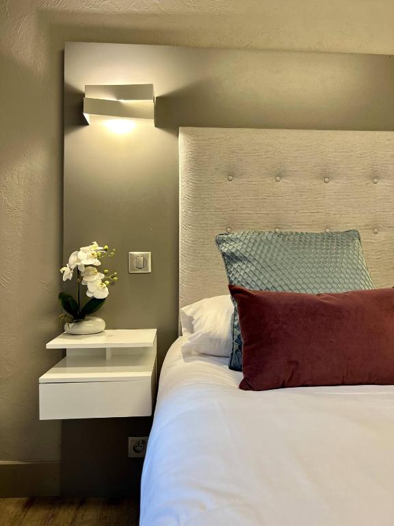 a bedroom with a white bed with a nightstand and flowers at Hotel La Calanque in Mandelieu-La Napoule