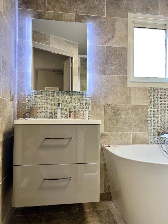 a bathroom with a tub and a sink and a mirror at Hotel La Calanque in Mandelieu-La Napoule