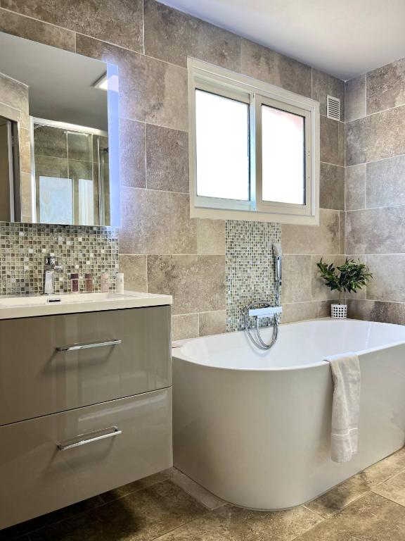 a bathroom with a tub and a sink at Hotel La Calanque in Mandelieu-La Napoule