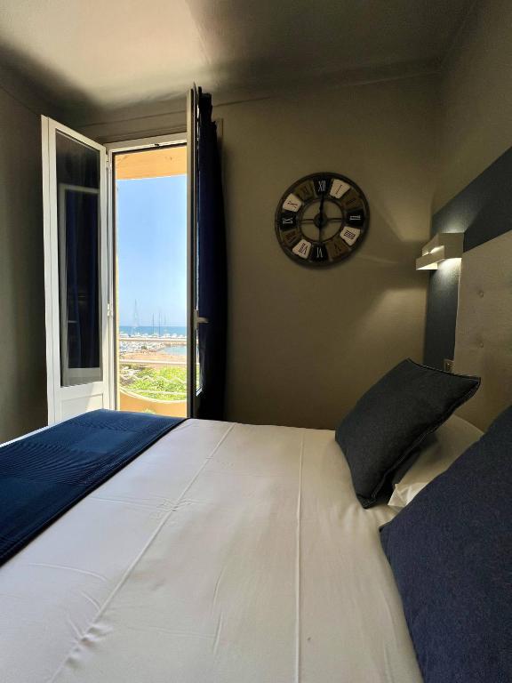 a bedroom with a large bed with a clock on the wall at Hotel La Calanque in Mandelieu-La Napoule