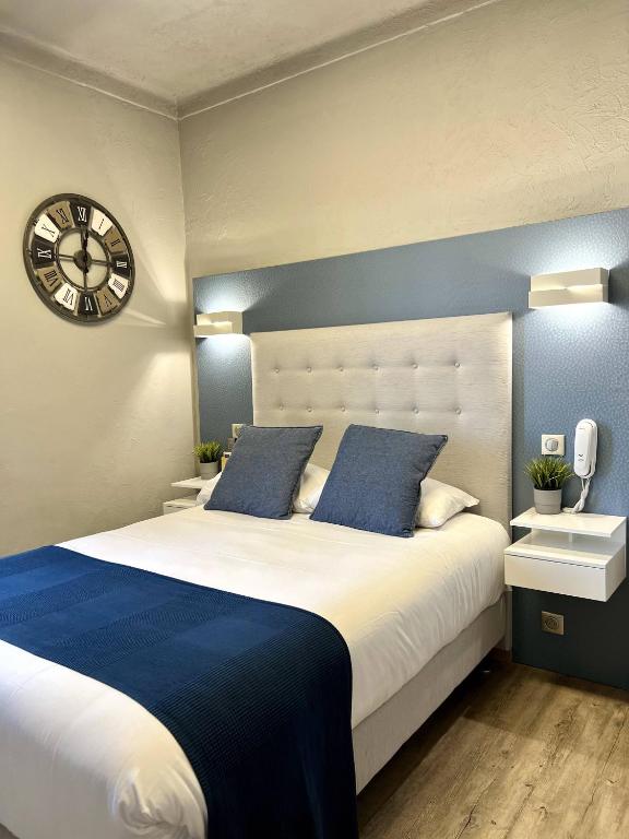 a bedroom with a large bed with a clock on the wall at Hotel La Calanque in Mandelieu-La Napoule