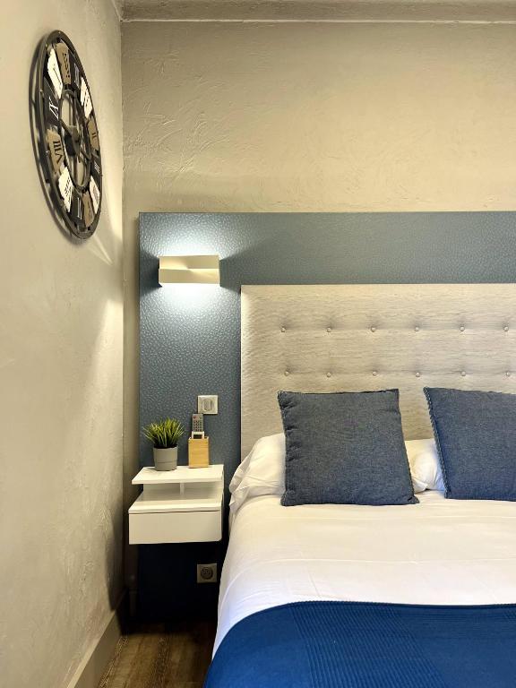 a bedroom with a bed and a clock on the wall at Hotel La Calanque in Mandelieu-La Napoule