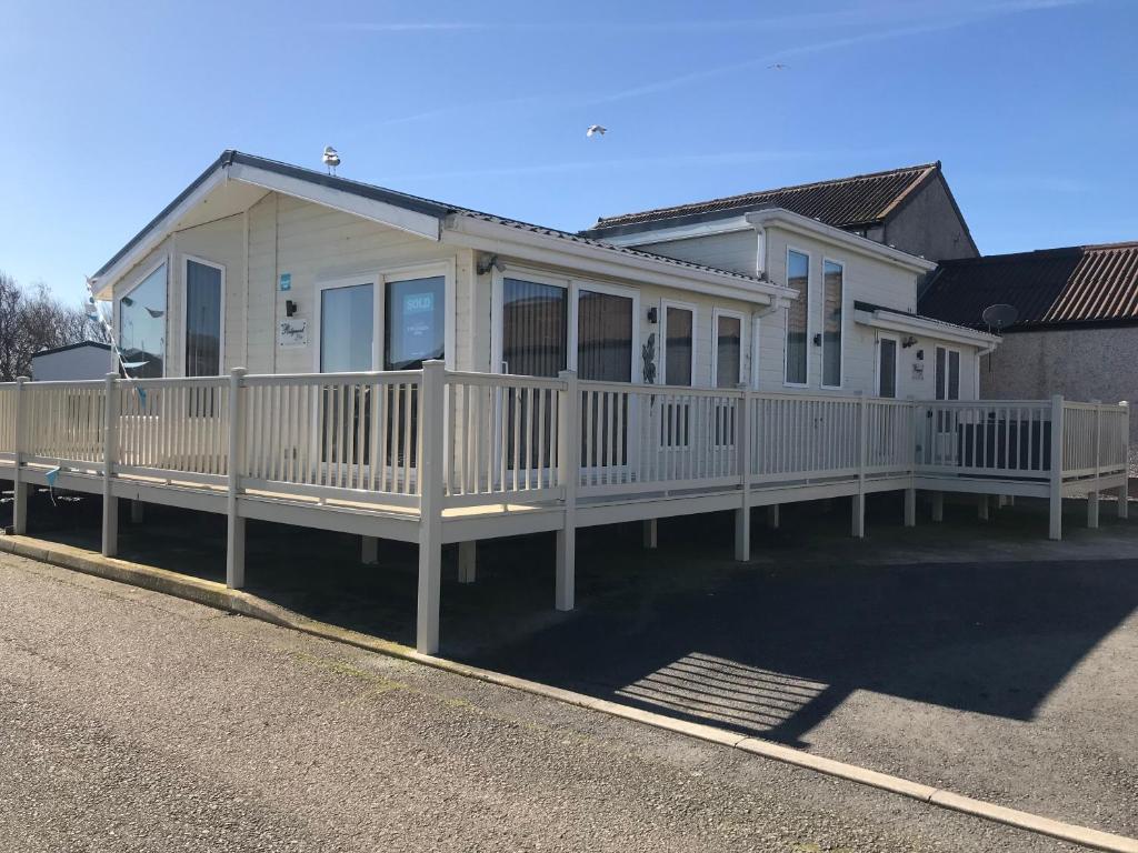 a white house with a white fence on a street at Hot Tub Accommodation North Wales Lodge in Rhyl