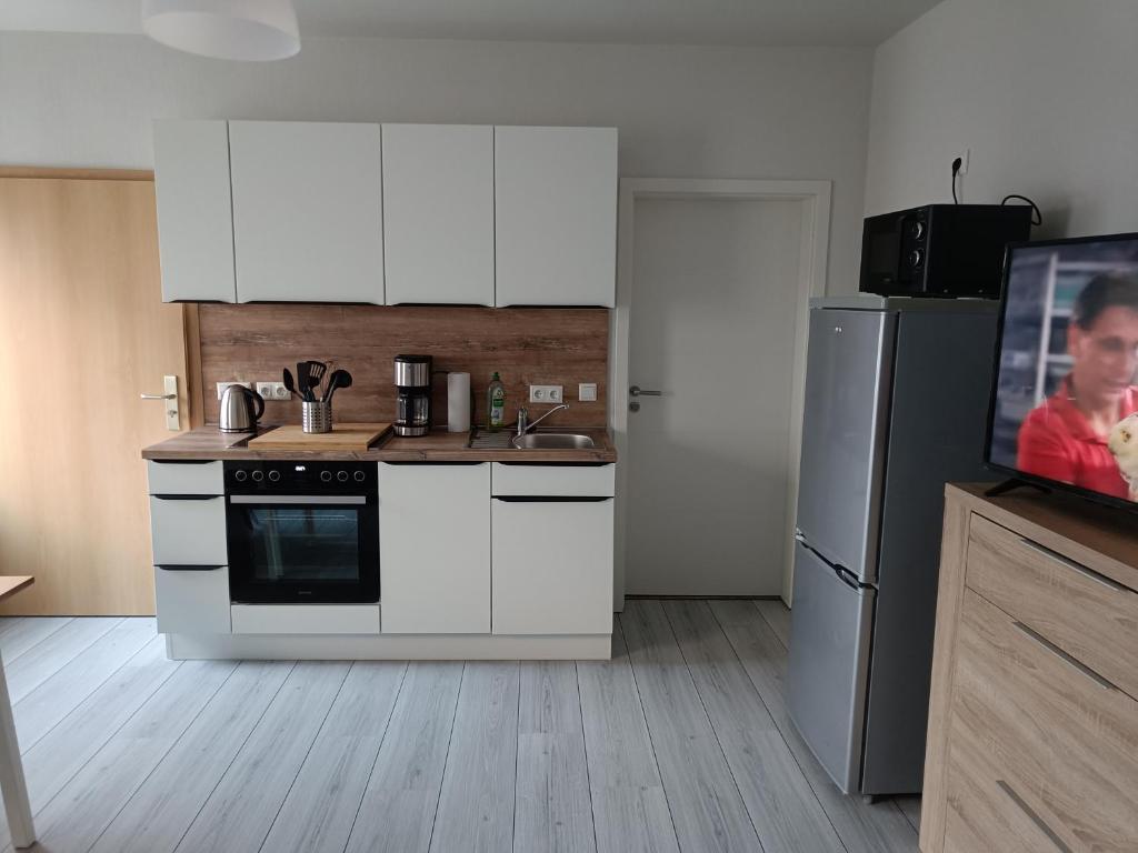 a kitchen with white cabinets and a refrigerator and a tv at FeWo Bismarck 32 - 1Raum in Stendal