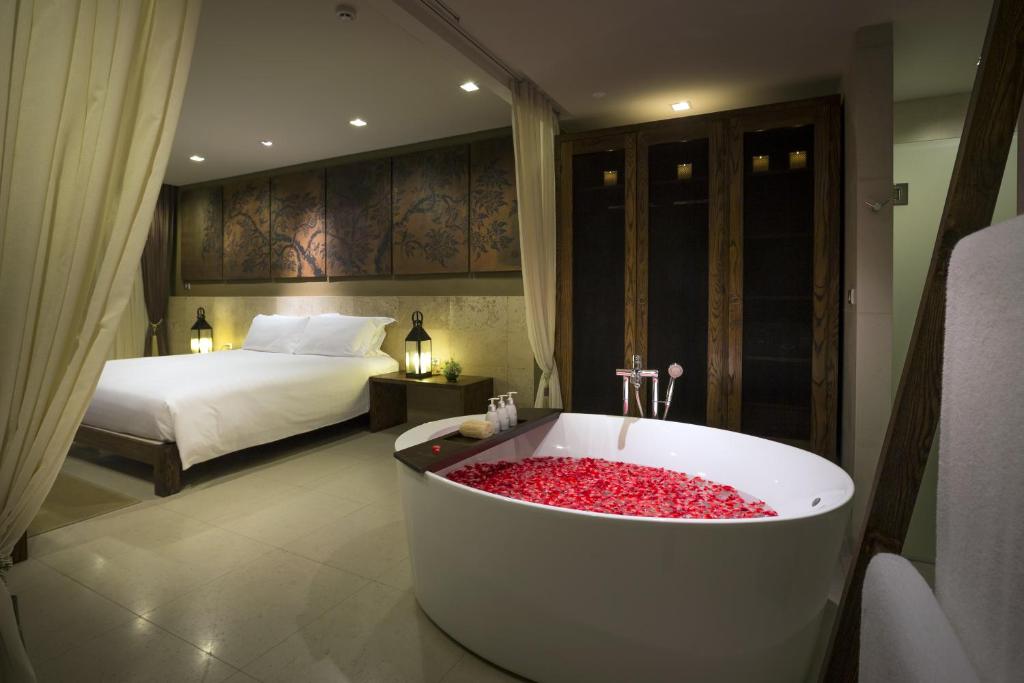 a bathroom with a tub with a bed and a bedroom at Sunsuri Phuket - SHA Plus in Nai Harn Beach