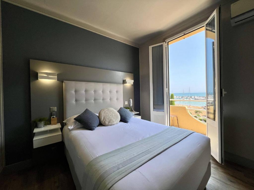 a bedroom with a large bed and a large window at Hotel La Calanque in Mandelieu-La Napoule