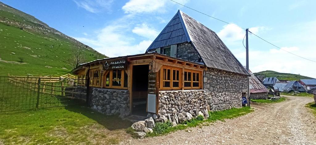 un pequeño edificio de piedra con techo negro en Na krovu svijeta, en Lukomir