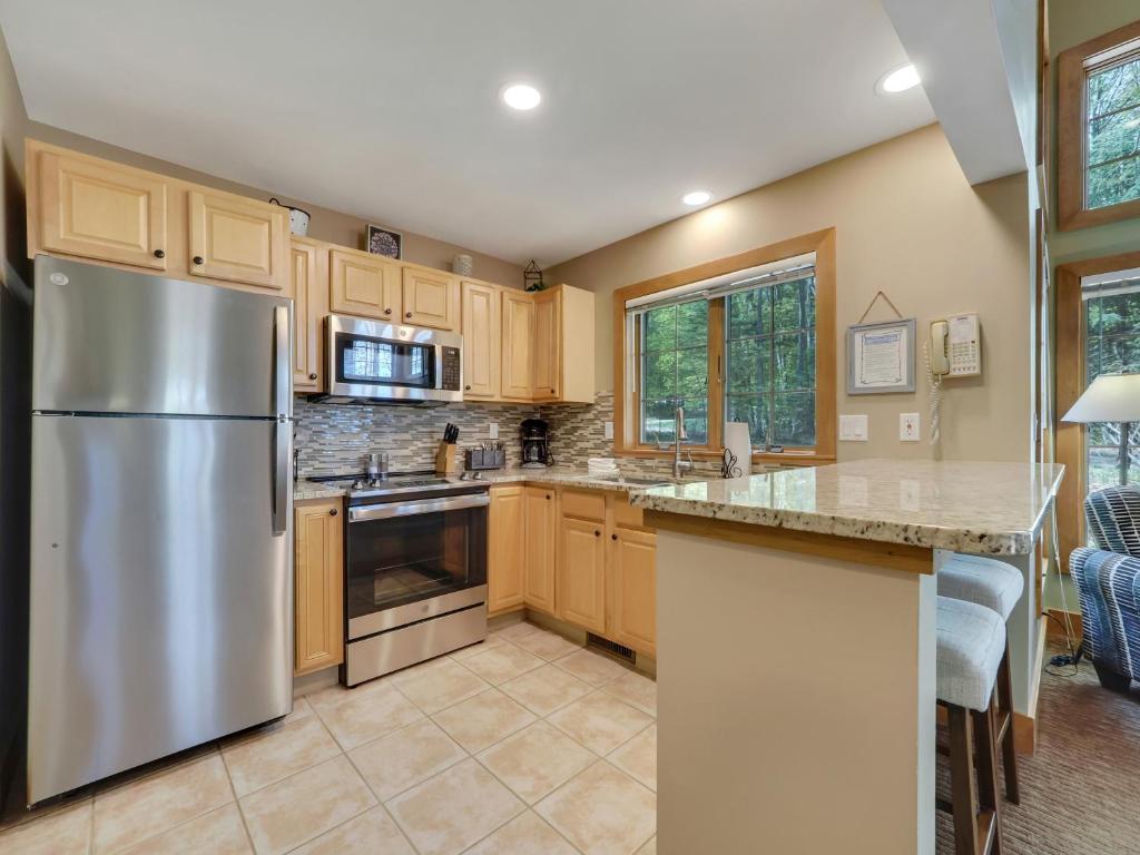 a kitchen with wooden cabinets and a stainless steel refrigerator at 658 Disciples Village Condo in Boyne Falls