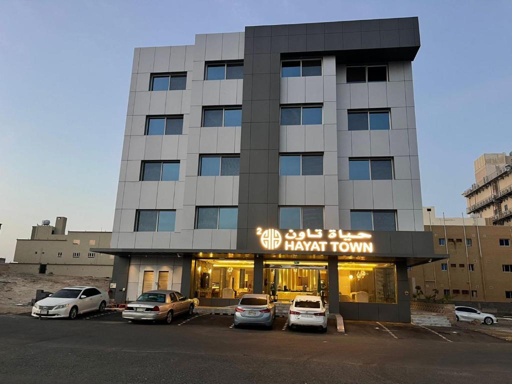 a building with cars parked in a parking lot at فندق حياة تاون 2 in Umm Lujj