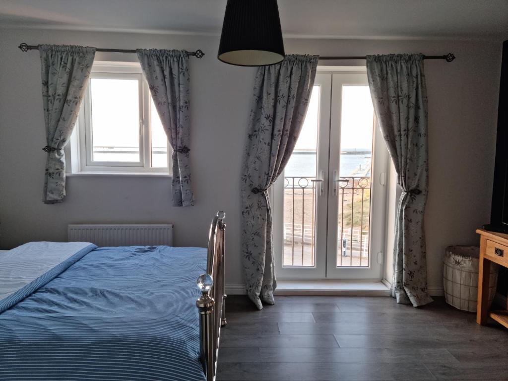a bedroom with a bed and a large window at Beach View Couples Retreat Aberavon Beach Direct Seafront panoramic Sea Views large driveway parking in Port Talbot