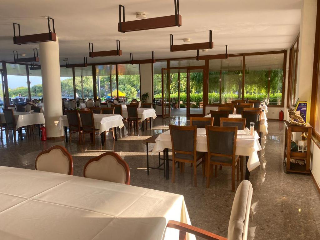 un restaurante con mesas y sillas blancas y ventanas en Zu Tiny House Hotel & Restaurant, en Urla