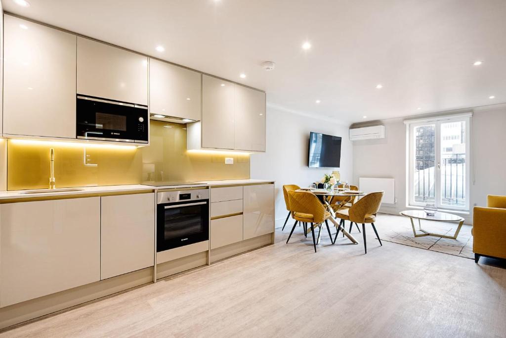 een keuken met witte kasten en een tafel met stoelen bij Marble Arch Suite 5-Hosted by Sweetstay in Londen