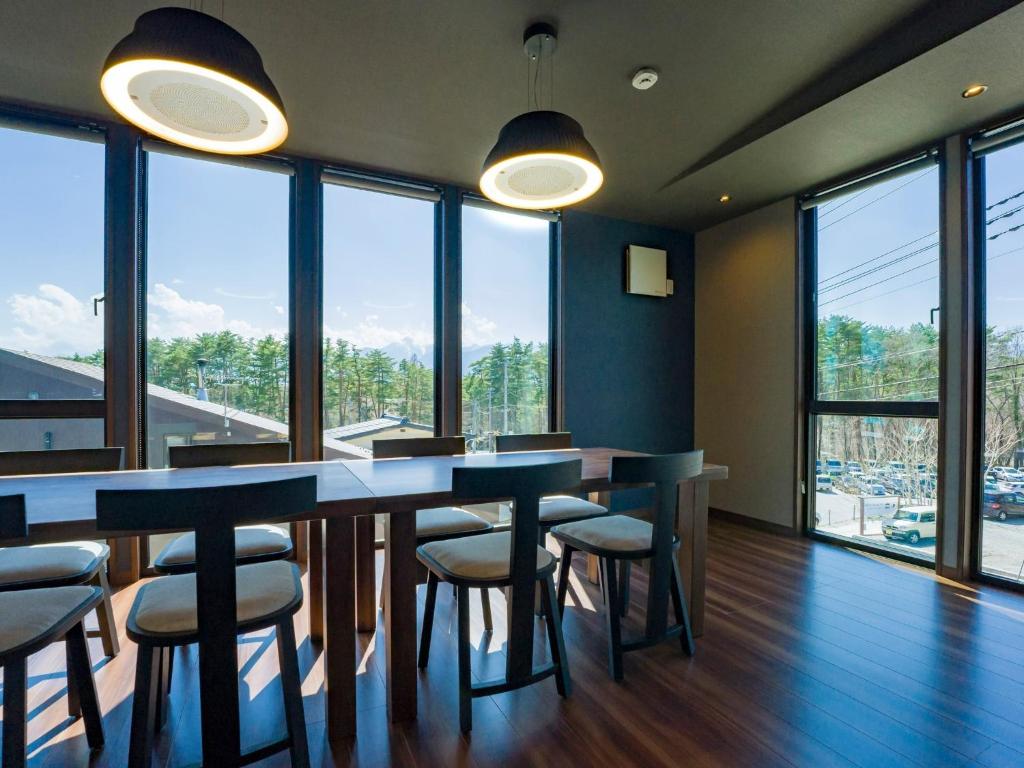 - une salle à manger avec une table, des chaises et des fenêtres dans l'établissement Rakuten STAY VILLA Yatsugatake - 105 Stylish Design -, à Hokuto