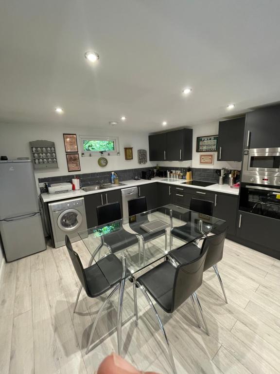 a kitchen with a glass table and black chairs at The Cabin, Arkley, Barnet in Barnet