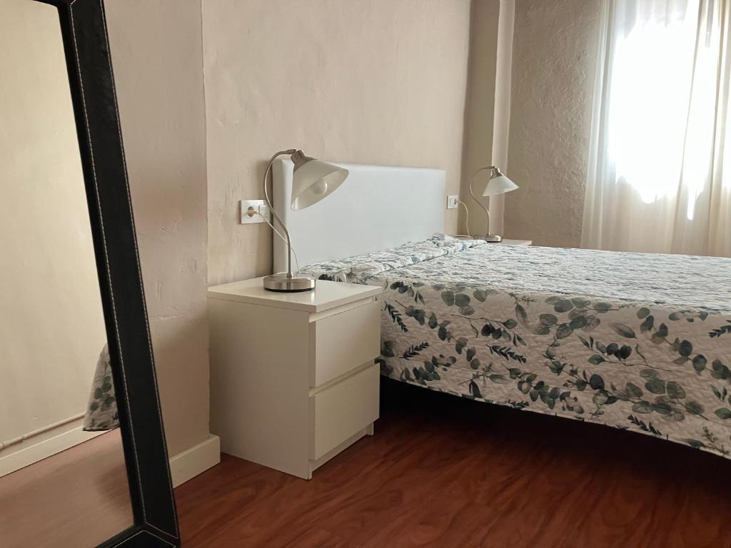 a bedroom with a bed with a lamp on a dresser at APARTAMENTO CALLE CURIA 6 in Pamplona