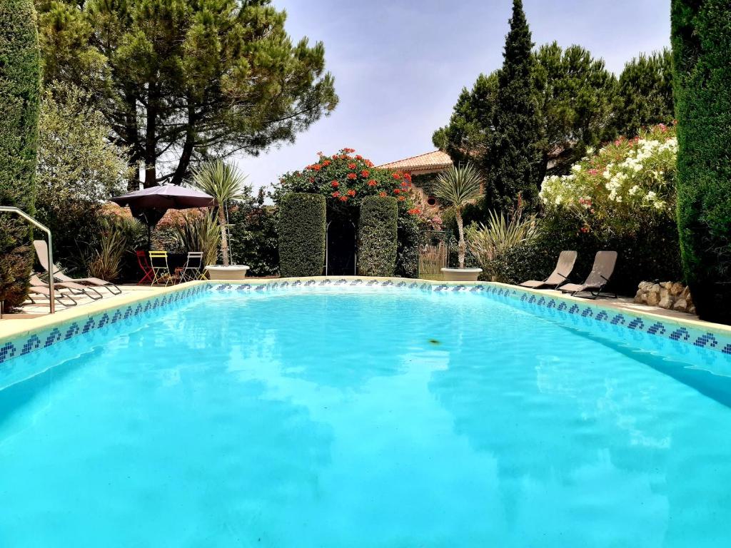 a large blue swimming pool with chairs and trees at Magnifique maison de campagne au cœur d&#39;un domaine viticole in Cazouls-lès-Béziers