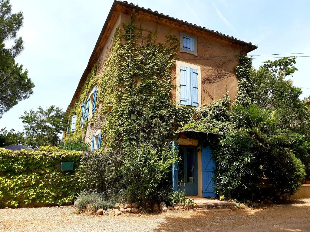 an ivy covered house with a blue door at Magnifique maison de campagne au cœur d&#39;un domaine viticole in Cazouls-lès-Béziers