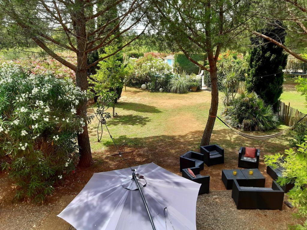 a patio with an umbrella and tables and chairs at Magnifique maison de campagne au cœur d&#39;un domaine viticole in Cazouls-lès-Béziers