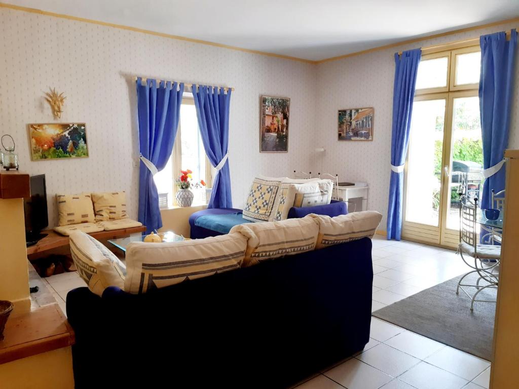 a living room with a couch and blue curtains at Magnifique maison de campagne au cœur d&#39;un domaine viticole in Cazouls-lès-Béziers