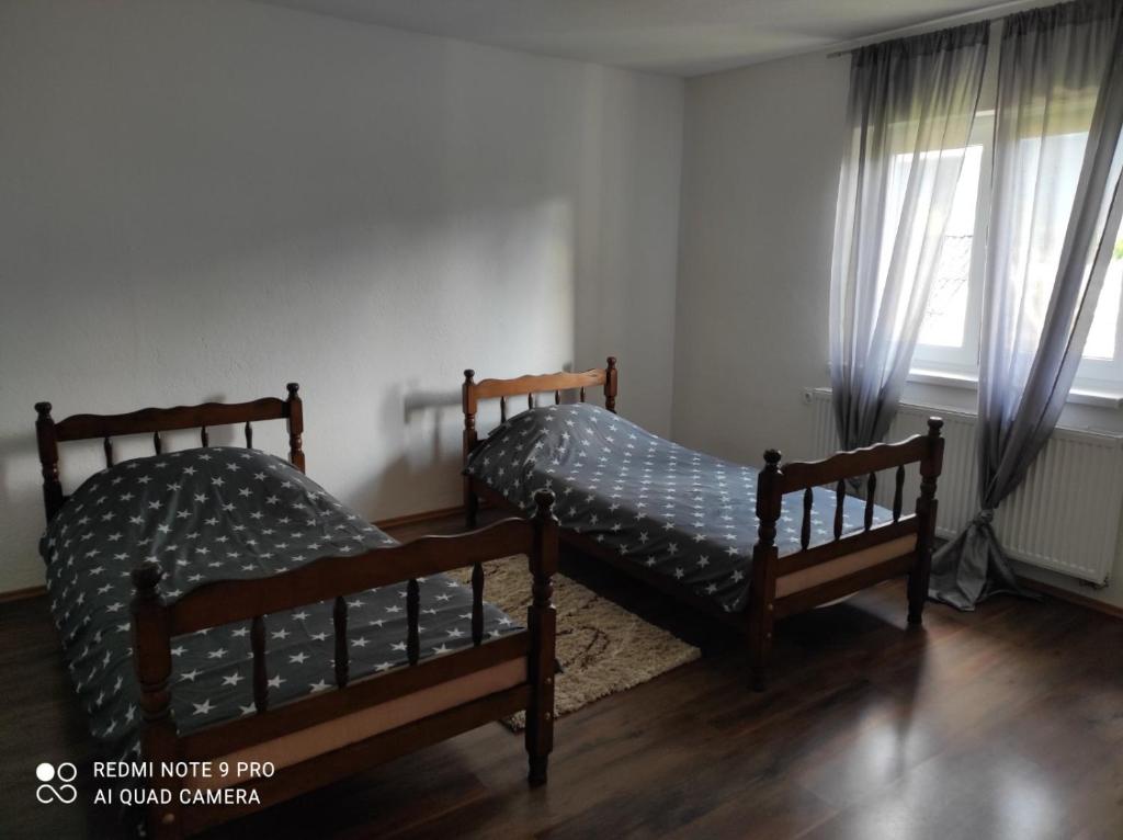 two beds in a room with two windows at Meri rooms in Bihać