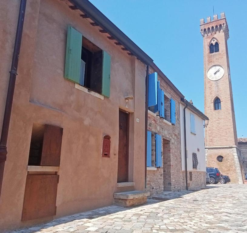 a building with a clock tower next to a street at CasAlice Room&Breakfast in centro storico in Santarcangelo di Romagna