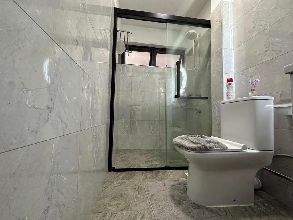 een badkamer met een toilet en een glazen douche bij Sandib comfy homes in Kampala