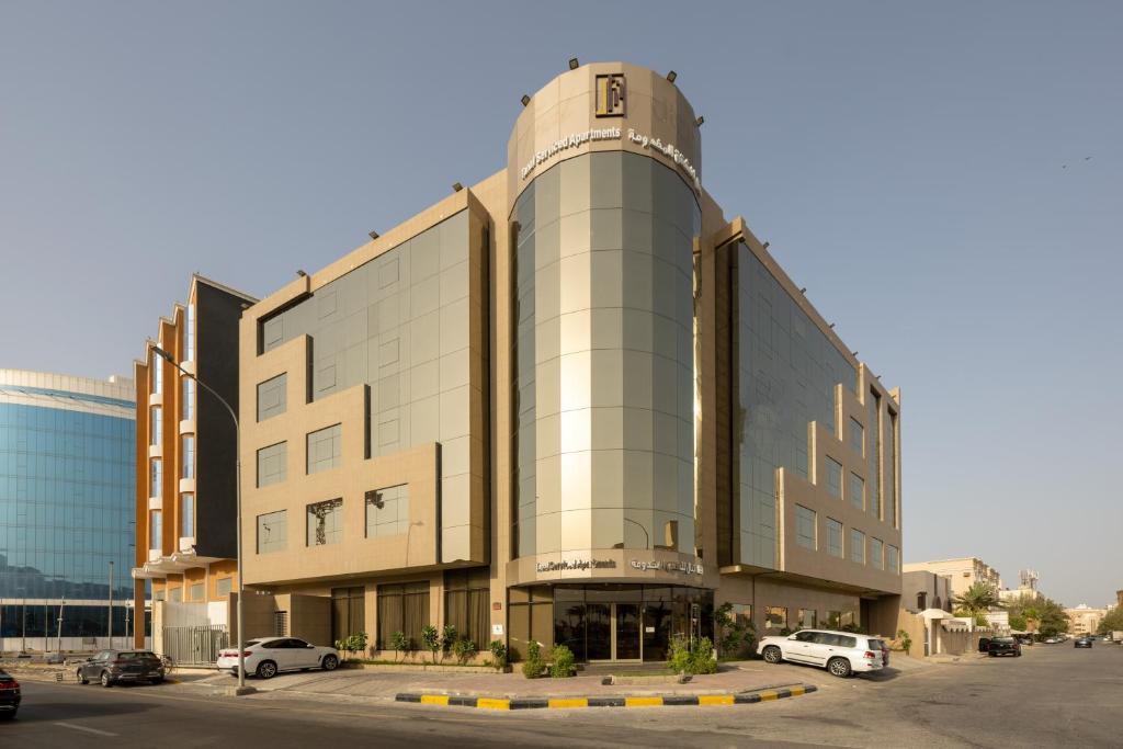 um grande edifício com carros estacionados num parque de estacionamento em Tanal Serviced Apartments em Al Khobar