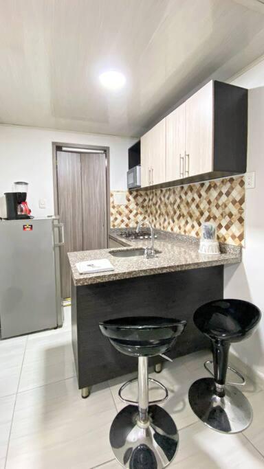 a kitchen with a counter and two bar stools at Apartahotel 222 Apartamento 503 in Pereira