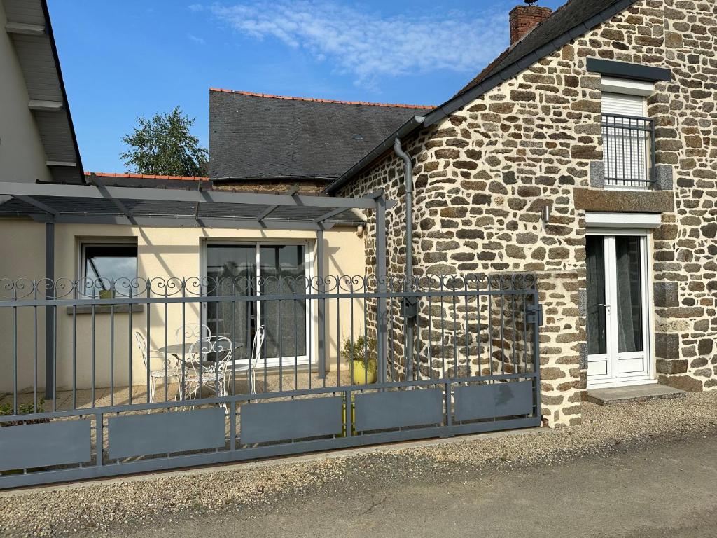 a brick building with a gate and a house at La maison du Chêne 2 in Miniac-Morvan