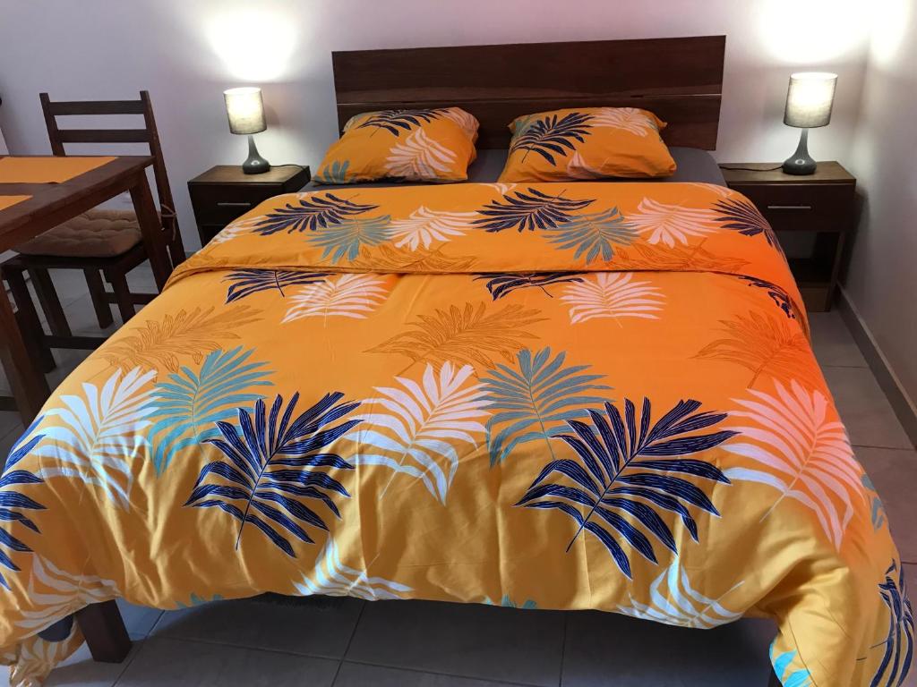 Una cama con colcha de color naranja con palmeras. en Discrétion, en Saint-Laurent-du-Maroni