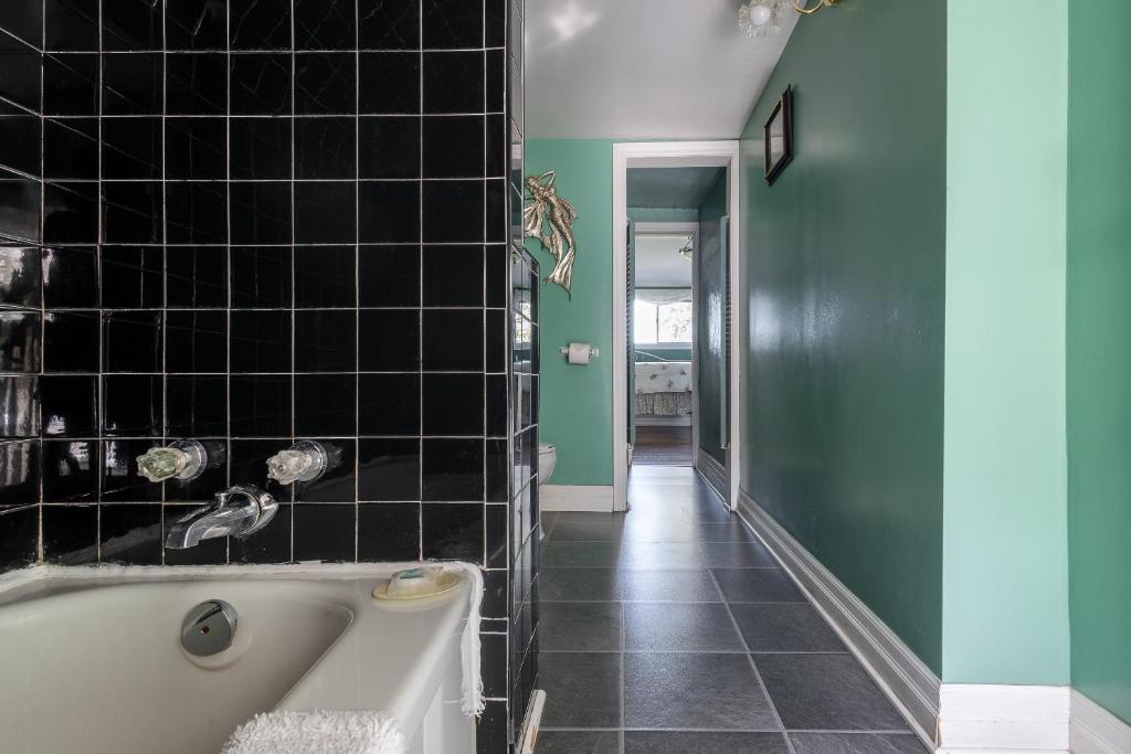 a bath tub in a bathroom with black tiles at Chestnut Inn in Niagara Falls