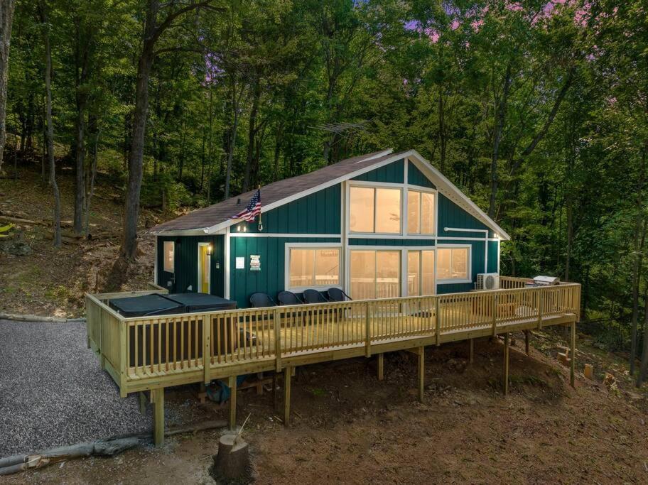a green house with a large deck in the woods at Forest Ridge Cabin - Hot Tub, Wi-Fi, National Park 15 Min, Fire Pit in Elkton