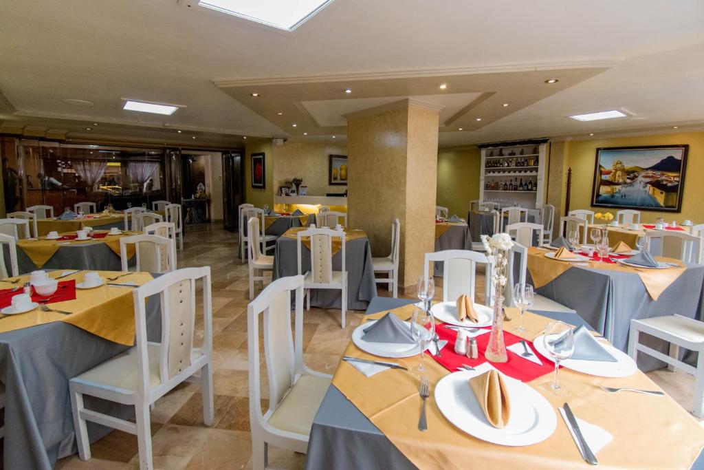 a restaurant with tables and chairs with plates and napkins at Grand Hotel Loja in Loja
